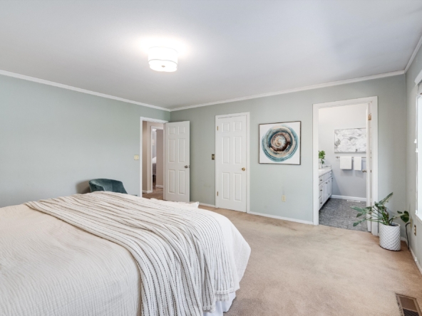 Bedroom with sage-green walls, two white doors, abstract spiral artwork, and a large window on the right side.
